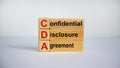 Concept words `CDA, confidential disclosure agreement` on cubes on a beautiful blue background. Business concept, copy space