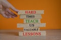 Concept words Hard times teach us valuable lessons on brick blocks on a beautiful orange background. Royalty Free Stock Photo