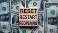 Concept words `reset, restart, reopening` on wooden blocks on a beautiful background from dollar bills