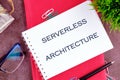 Concept words SERVERLESS ARCHITECTURE in a mini notebook on a business book, close-up. Copy space Royalty Free Stock Photo