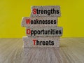 Concept words SWOT strengths weaknesses opportunities brick blocks on beautiful yellow backgroun