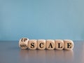 Concept words Upscale or Downscale on wooden cubes. Beautiful grey table blue background. Business upscale or downscale concept.