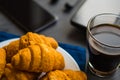 Concept of work. Top view. Macro shot of Smartphone and Laptop fresh croissants and coffee black background . Mate moody color.