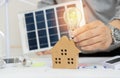 Concept working for clean energy and saving power in nature. hand holding light bulb on the house model Royalty Free Stock Photo