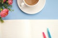 Concept workplace. White cup of coffee with milk, white open notebook for notes, ballpoint pen, pink flower on a blue background,