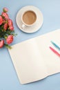 Concept workplace. White cup of coffee with milk, white open notebook for notes, ballpoint pen, pink flower on a blue background,