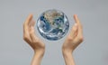 The concept of the world is in your hands. Two female hands hold the globe against an isolated gray background. Copy space,