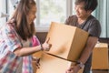 Concept young couple moving house. Asian woman helping man carry cardboard box to move in new house Royalty Free Stock Photo