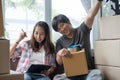 Asian young couple make high five hands after finish packing cardboard box prepare for relocation apartment