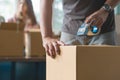 Concept young couple moving house. Close-up hand of man use tape sealing cardboard box Royalty Free Stock Photo