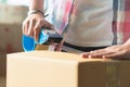 Concept young couple moving house. hand of woman use tape sealing cardboard box Royalty Free Stock Photo