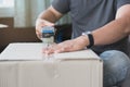 Concept young couple moving house. Close-up hand of woman use tape sealing cardboard box Royalty Free Stock Photo