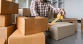 Concept young man moving house. Close up hand of man use tape sealing cardboard box Royalty Free Stock Photo