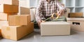 Concept young man moving house. Close up hand of man use tape sealing cardboard box Royalty Free Stock Photo