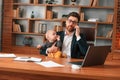 Conception of multitasks. Businessman in formal clothes is working indoors. With toddler Royalty Free Stock Photo