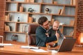 Conception of multitasks. Businessman in formal clothes is working indoors. With toddler Royalty Free Stock Photo