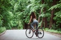 Conception of speed and motion. Female cyclist on a bike on asphalt road in the forest at daytime Royalty Free Stock Photo