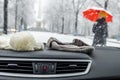 Conceptional winter shot of beanies in a car behind the front window while lady with red umbrella walks by