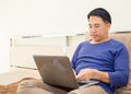 Concepts technology with People lifestyle. Asian man working on laptop computer and talking mobile phone on the bed Royalty Free Stock Photo