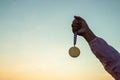 Concepts of victory, success, Hands with an award winning medal on beautiful sunset sky background