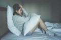 Portrait of depressed woman sitting alone on the bed in the bedroom. Royalty Free Stock Photo