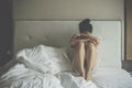 Portrait of depressed woman sitting alone on the bed in the bedroom. Royalty Free Stock Photo