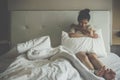 Portrait of depressed woman sitting alone on the bed in the bedroom. Royalty Free Stock Photo