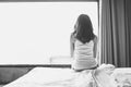 Portrait of depressed woman sitting alone on bed in bedroom. Royalty Free Stock Photo