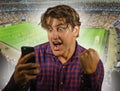 Conceptual composite with happy and excited man with mobile phone and soccer background in online sport bet and internet gambling