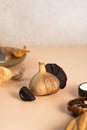 A conceptual composition of fermented food. Black garlic bulbs, cloves and peel lie on a beige table. Healthy nutrition, Royalty Free Stock Photo