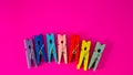 Conceptual composition, five clothespins of color - red, pink, orange, yellow, fuchs on a black background
