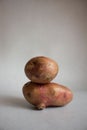 Conceptual creative still life with balancing fresh red potatoes on a light gray background. Equilibrium floating food balance.