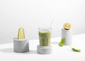 Conceptual creative still life with green fruits and smoothie on concrete podiums