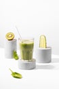 Conceptual creative still life with green fruits and smoothie on concrete podiums