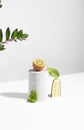 Conceptual creative still life with green fruits and cucumber on concrete podiums on a white background