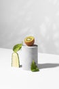 Conceptual creative still life with green fruits and cucumber on concrete podiums on a white background