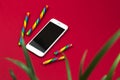 Conceptual desktop with smartphone and houseplant on red background and sweets, minimal design