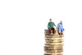 Miniture figure retired couple sat on a stack of pound coins