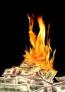 Conceptual finance image of burning pile of money, dollar bills, and fire flames in black background Royalty Free Stock Photo