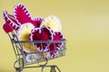 Conceptual grocery basket with colored soft hearts on a yellow background.