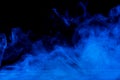 Conceptual image of blue smoke isolated on dark black background and wooden table Royalty Free Stock Photo