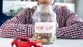 Conceptual image of buying new car. Man with glass jar full of coins and toy car on table Royalty Free Stock Photo