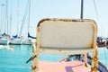 Conceptual Image of Empty Vintage Chair Standing at Sea Harbor Overlooking Marina with Moored Yachts Sailing Boats. Beautiful Sea