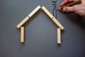 Conceptual image of family values and adoption. House from wooden blocks on beautiful grey background. Male hand draws with black Royalty Free Stock Photo