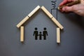Conceptual image of family values and adoption. House from wooden blocks on beautiful grey background. Male hand draws with black Royalty Free Stock Photo