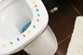 Conceptual image of a hemorrhoid disease with multi-colored thumbtacks on toilet bowl cover