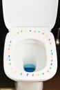 Conceptual image of a hemorrhoid disease with multi-colored thumbtacks on toilet bowl cover