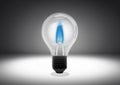 Isolated object shot of a light bulb with a blue flame inside on a dark background Royalty Free Stock Photo