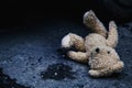 Conceptual image: lost childhood, loneliness, pain and depression. Dirty toy Teddy bear lying down outdoors. Copy space for text Royalty Free Stock Photo