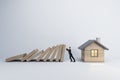 A conceptual image of a man preventing a row of falling dominos from crashing into a small house, symbolizing protection and Royalty Free Stock Photo